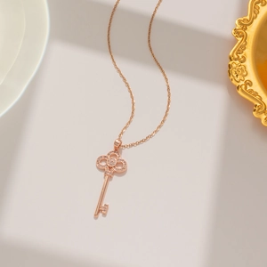 Macro shot of rose gold key pendant with small crystals on a delicate cable chain