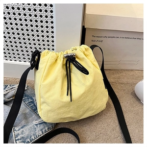 Detailed shot of yellow nylon bucket bag with drawstring closure and metal hardware detail