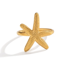 Détail d'une bague étoile de mer dorée avec texture martelée et anneau en métal poli
