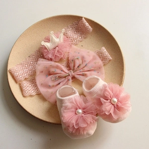 Pink lace baby headband with mesh crown and matching bow socks with pearls in a ceramic tray