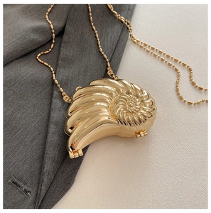 Detailansicht der goldenen Schneckenhaus-Abendtasche mit Spiralstruktur und Perlenkette