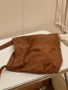 Macro detail of caramel brown suede tote bag with intricate paisley embroidery patterns
