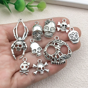 Set of retro silver skull alloy pendants for DIY jewelry making shown in hand for scale