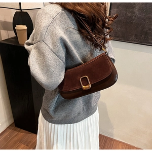 Detail of dark brown underarm bag showing contrast stitching and gold buckle texture