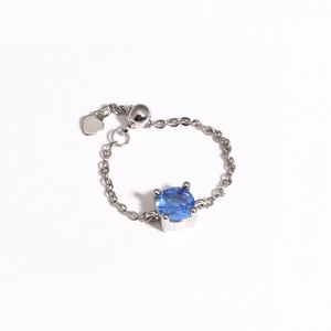 Detail of adjustable silver chain ring with a blue gemstone and tiny heart charm