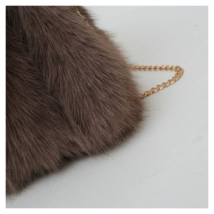 Macro shot of fluffy brown faux fur texture on tote bag with elegant gold chain strap