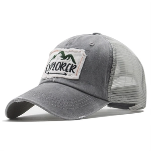 Close-up of gray distressed mesh trucker hat with EXPLORER patch and frayed brim