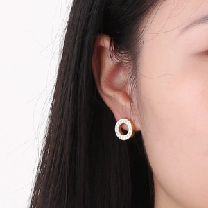 Close-up of a woman wearing gold-tone circular earrings with clear sparkling rhinestones