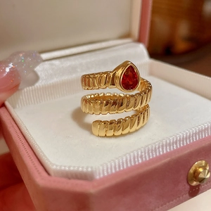 Detail of vintage gold spiral ring with a red pear-shaped gemstone on pink velvet