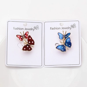 Detail of red and blue enamel butterfly brooches with white pearls on a display card