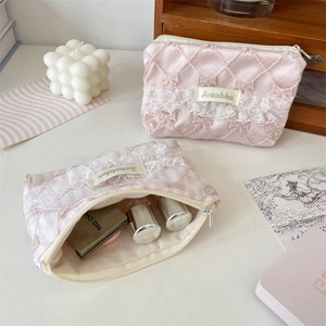Close-up of pink quilted cosmetic bag with white lace trim and zipper detail