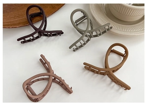 Matte finish cross-over claw clips in earth tones on a minimalist white surface