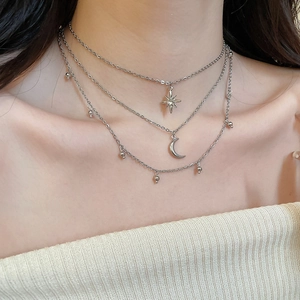 Close-up of layered silver star and moon pendant necklaces on female model