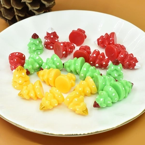 Close-up of miniature resin Christmas tree charms in red, green, and yellow for DIY crafts