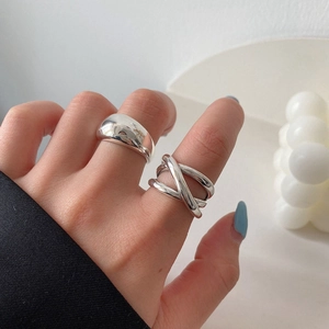 Close-up of layered silver rings set with wide polished and crisscross band designs