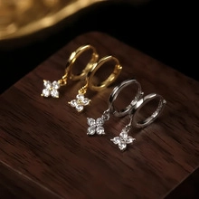 Dettaglio di orecchini a fiore in oro e argento con brillanti pietre di zircone