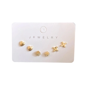 Three-pair gold earring set with heart, cube, and X shapes on a white jewelry display card