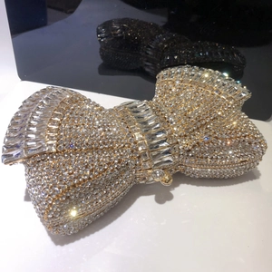 Close-up of golden bow-shaped evening clutch bag featuring intricate crystal embellishments