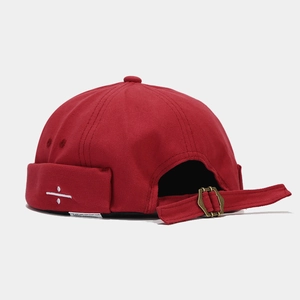 Macro detail of the 100% cotton fabric and adjustable metal strap on the red docker hat