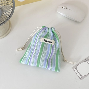 Detail of striped drawstring cosmetic pouch showing green and purple canvas texture