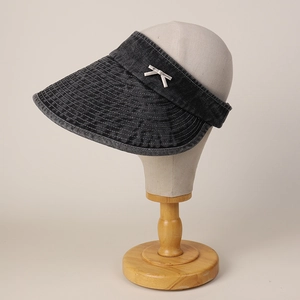 Detail of black denim sun visor with decorative white bow and stitched wide brim