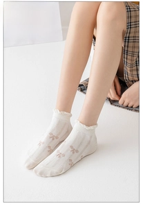 Close-up of white thin cotton socks featuring elegant ruffle edge and embroidered bow detail