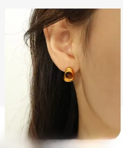 Detailed view of irregular geometric gold earrings with dark brown gemstone inlay