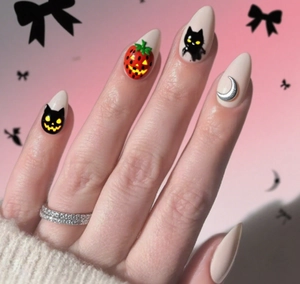 Detail of Halloween stiletto nails with black cat, moon charm, and pumpkin strawberry