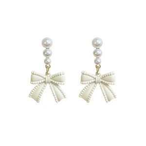 Detail shot of long bowknot earrings with triple cream pearls and vintage scalloped edges