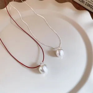 Detail of apple pendants with red leather cord and silver chain in a ceramic dish