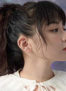 Detail view of small 925 silver flower stud earrings in white and pink on model