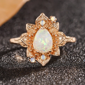 Macro di anello loto in oro rosa con opale a goccia bianco e dettagli floreali vintage