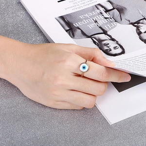 Rose gold evil eye ring featuring blue and white enamel design worn by model