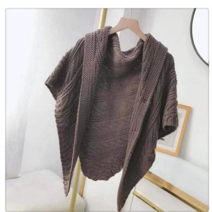 Close-up of dark brown knitted poncho with elegant leather buckle detail on hanger