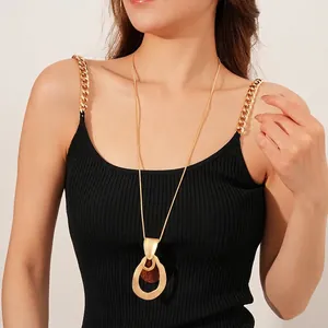 Minimalist gold teardrop pendant necklace with brown insert worn on black dress