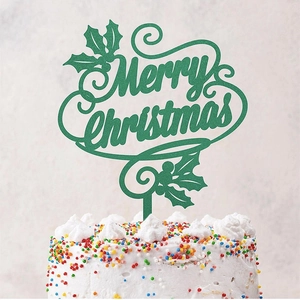 Detail of green glitter Merry Christmas acrylic cake topper with holly leaves on frosting
