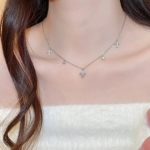 Detail shot of a silver necklace with zircon cross pendants worn by a female model