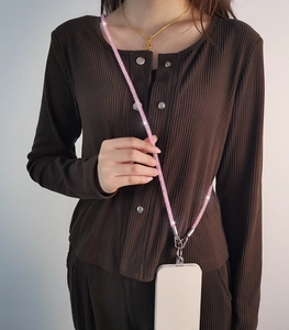 Close-up of pink glitter crossbody phone lanyard worn by a model in brown cardigan