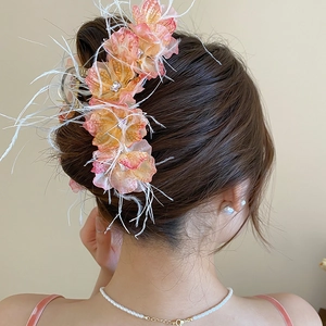 Détail de la pince à cheveux avec fleur dégradée pêche, cristaux et plumes blanches
