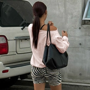 Detail view of a pink long sleeve cropped top with zebra pattern shorts and a black tote bag