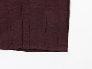 Detailed close-up of dark burgundy crinkled fabric with reinforced hem stitching detail
