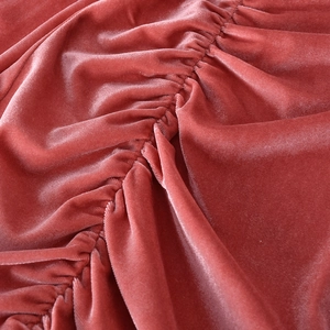 Détail du tissu en velours rose foncé avec des fronces élégantes et texture brillante