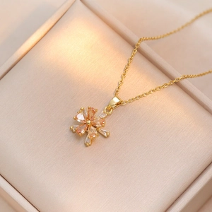 Macro detail of a golden rotating sunflower pendant with orange and white zircons