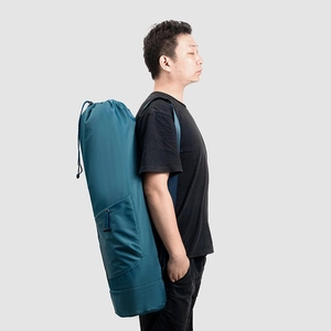 Detail of teal yoga mat bag with drawstring top and side pocket shown by male model