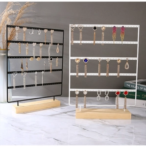 Detailed view of multi-tier metal jewelry stand with holes and a solid wood base