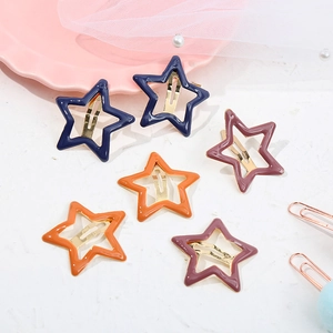 Flat lay showing colorful star-shaped metal hair clips in navy blue, orange and purple
