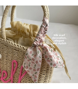 Detailed macro view of woven straw handbag with floral silk scarf and drawstring liner