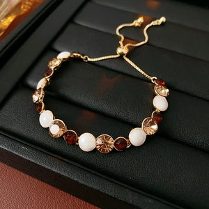 Détail macro du bracelet ajustable doré avec cristaux sur plateau en cuir noir
