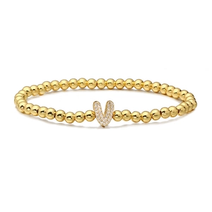Detailed close-up of golden beaded bracelet with a pavé-set letter V zircon charm