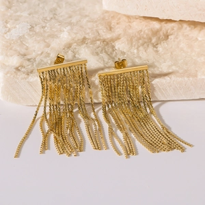 Exaggerated tassel earrings in 18k gold plated stainless steel on a white stone background